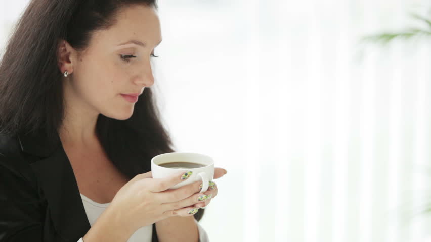 Beautiful young woman drinking coffee smiling and looking at camera
