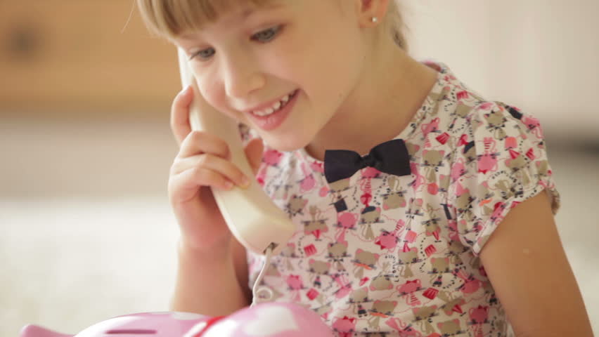 Funny little girl laughing and smiling at camera while talking on phone