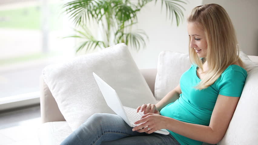 Attractive young woman sitting on sofa with laptop closing it and looking at