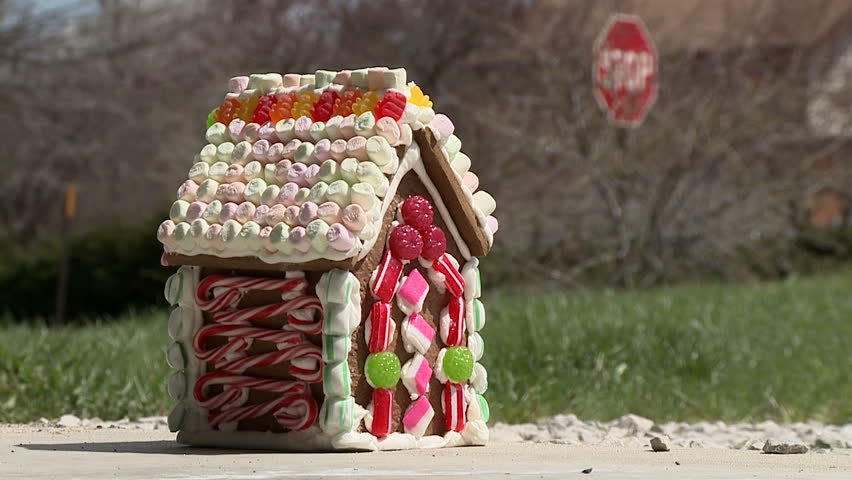 Gingerbread house is smashed with a hammer and appears to explode.  Street with