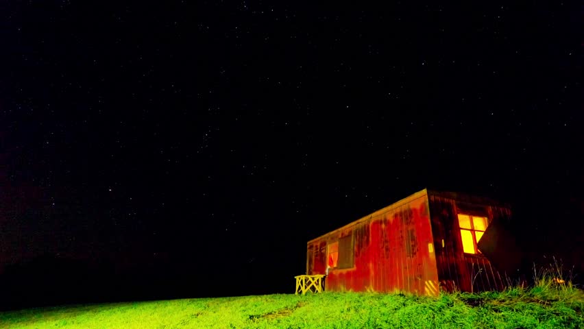 Night time-lapse with a shack and a starry sky