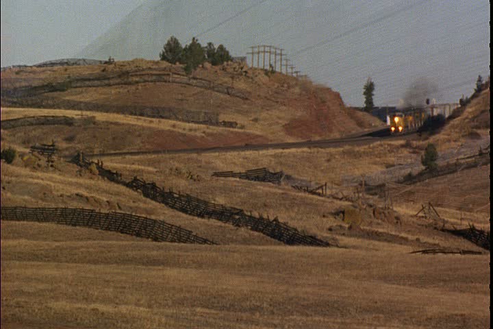 WS freight train approaching from between two hills on a grassy prairie in Laramie, Wyoming.