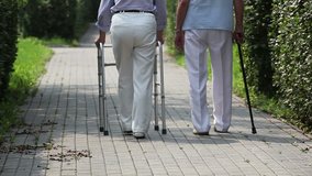 Elderly couple taking steps together with a help of a walker and a cane