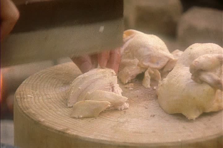 Re-creation of Chinese railroad workers camp in Auburn, California; CU chicken being cut on wooden block, hands transfer cut chicken to metal plate.
