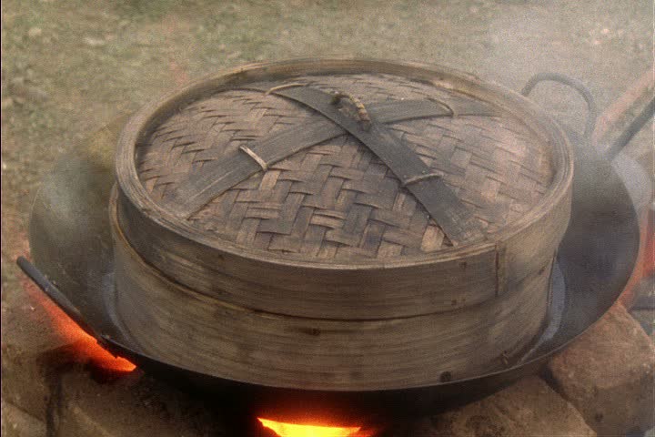 Re-creation of Chinese railroad workers camp in Auburn, California; CU bamboo steamer in wok. Hand places plate of uncooked food inside steamer and covers.