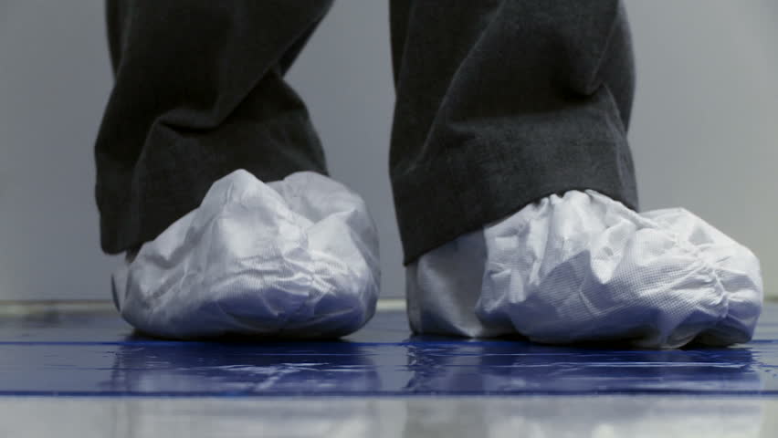 Close up of feet wearing paper boots coming out of a clean lab environment.