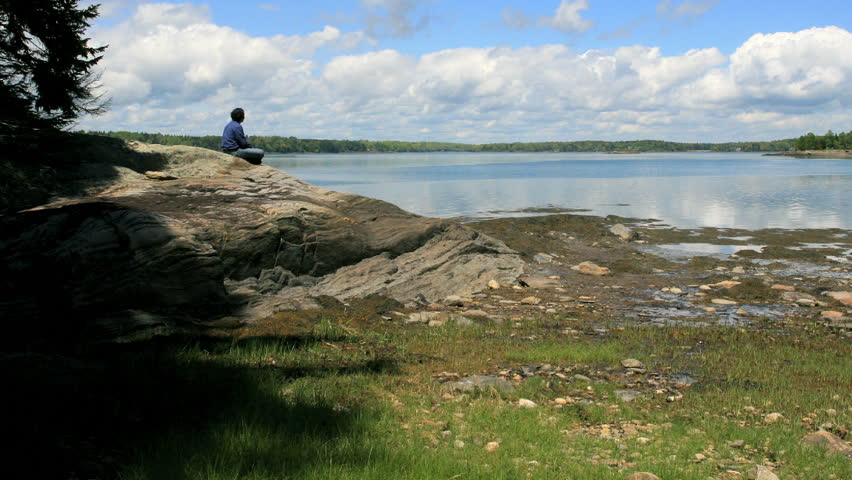 A man sits on rock and watches clouds go by.