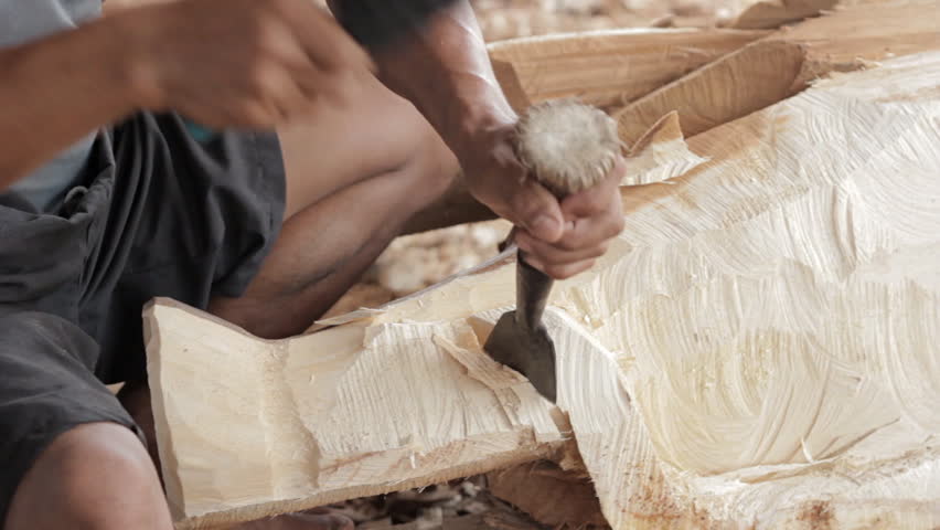 Traditional craftsman carving wood an elephant.