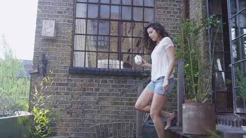 Attractive young woman enjoying a quiet moment in her garden on a sunny day. In slow motion. Arkivvideo