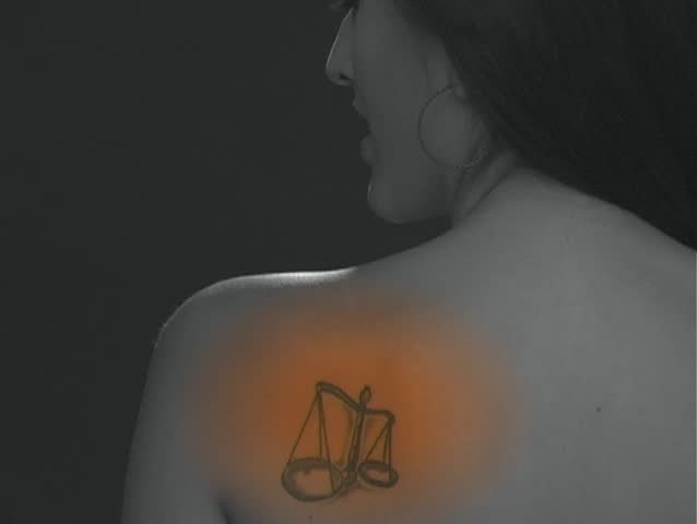 A beautiful young Latina rubs her left shoulder as if it