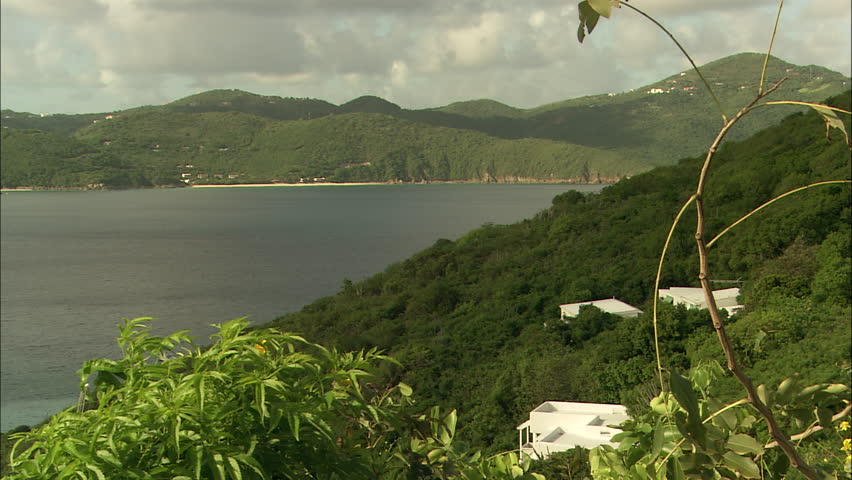 Bright white villas dot the hills around a pristine blue bay in Guana