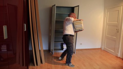 male cleans out a wardrobe with books and un-mounts the wardrobe, time lapse of several hours work