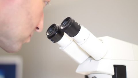 male in lab comes in scene and has a look in the microscope