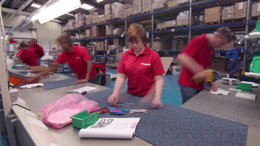 Time lapse of a busy group of workers on a factory assembly line, preparing electrical fittings.