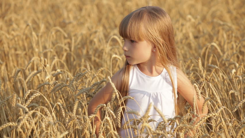 Beautiful little girl standing in wheat smiling and giving thumb up in slow