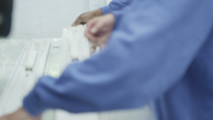 Mixed ethnicity team of male workers in a factory operating one of the machines and checking the quality of the products. 