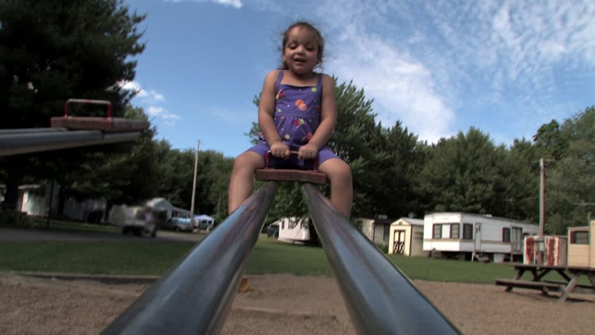 A young girl laughs on the see-saw.