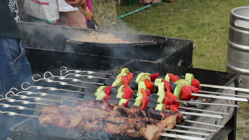 Preparing pilau outdoors, roasting kebab barbecue on brazier