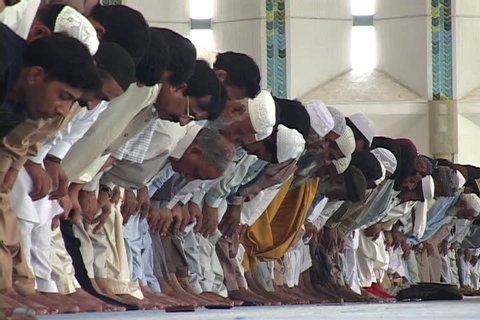 ISLAMABAD, PAKISTAN - CIRCA 2002: Row of Muslim men pray and bow to the ground.
