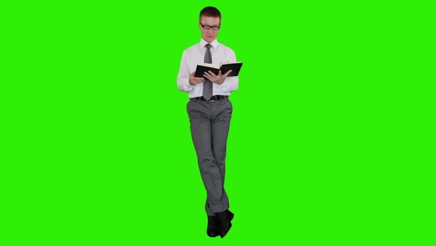 Young businessman with glasses reading a book and sitting, Green Screen