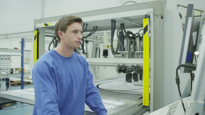 Cheerful mixed ethnicity factory workers looking at the VDU screen on one of the machines.