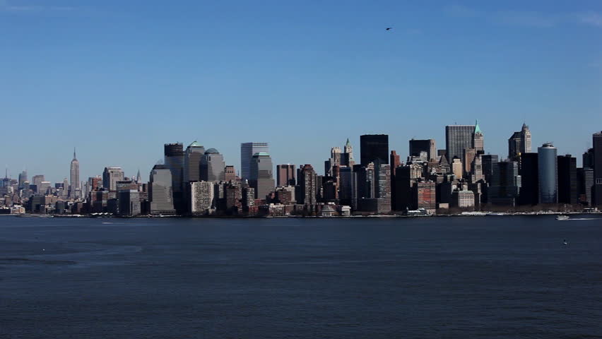 Pan over New York City skyline shot from Liberty Island with small helicopter