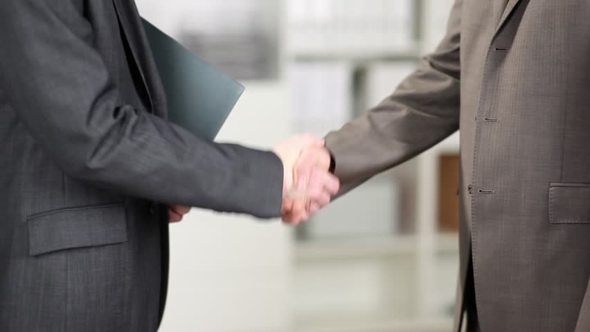 Two formal businessmen in suits shaking hands showing accord and agreement in clinching a deal, partnership or transaction | Shutterstock HD Video #4423340