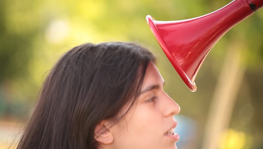 Young adult woman speaks to red speaking trumpet. Communications concept.
