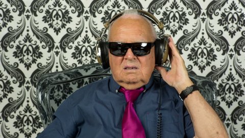 a very funky elderly grandpa dj listening to music on headphones
