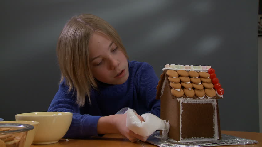 Boy sticking a door on to a gingerbread house.