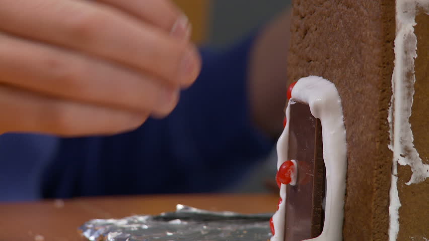 Decorating a chocolate door on a gingerbread house.