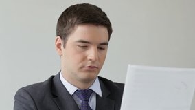 Businessman distracted from reading an important document gives the viewer a serious look