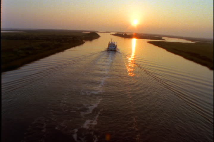 Sunset aerial follows riverboat and wake up the Mississippi River.