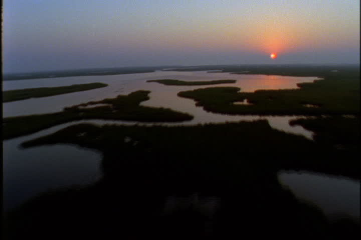 Sunset aerial over marshes, lowlands and lower Mississippi River.
