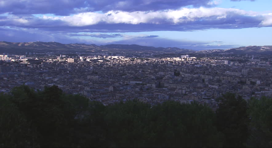 Panoramic cityscape of the city of Marseilles, with mountains looming in the