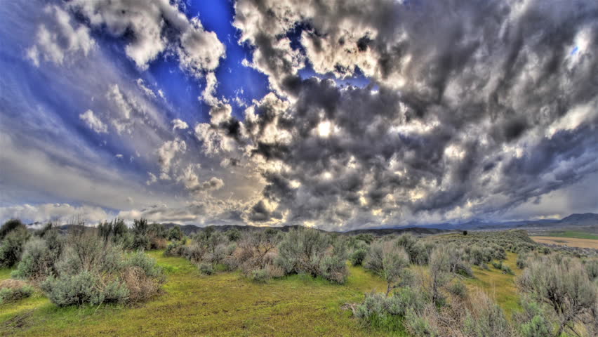 High definition tone mapped time lapse of cool clouds over a green field during