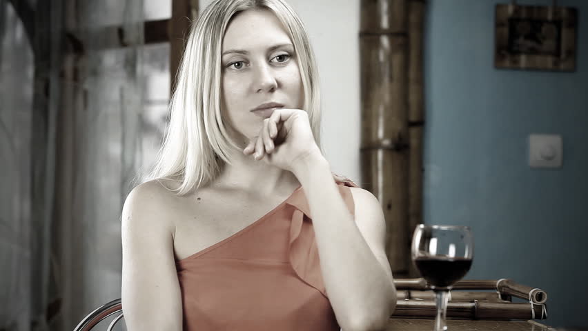 Beautiful blond woman drinks red wine in the bar