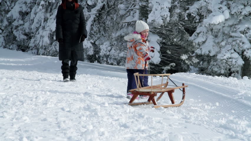 Little girl pulling sleigh in the winter surroundings