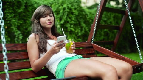 Young woman sending sms on bench swing in park
 Stockvideo