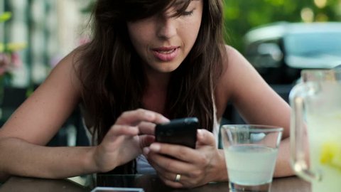 Young woman typing on smartphone in cafe
