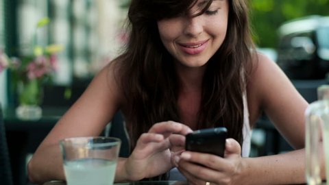 Happy young woman with smartphone in cafe
