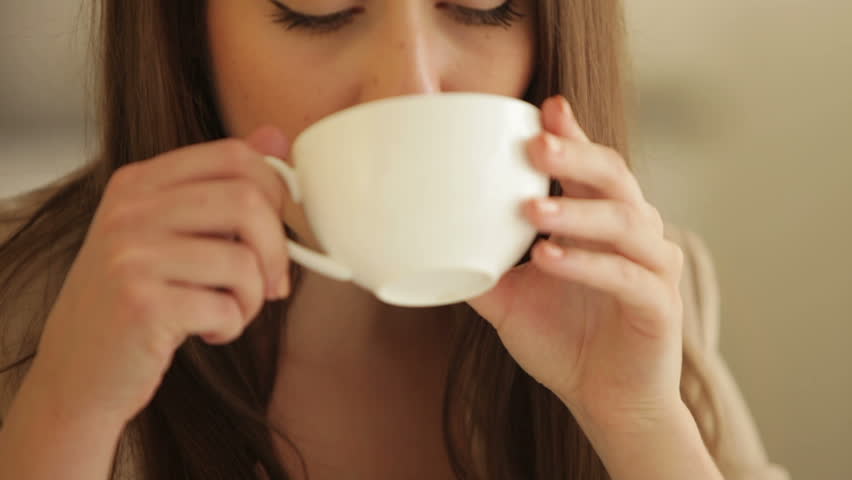 Young woman drinking tea and smiling at camera