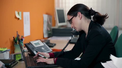Close up on business woman typing on PC and making a call