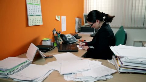 Business woman having a lot of work in office, making phone call