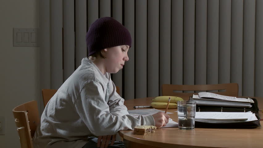 Teenager wearing a knitted cap and working on a homework assignment.  Sandwich,