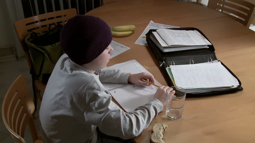 Teenager working on a homework assignment with a sandwich, bananas and empty