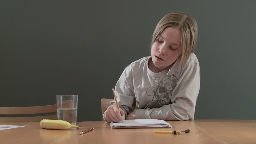Teenager working on a homework assignment with a banana and glass of soda on the