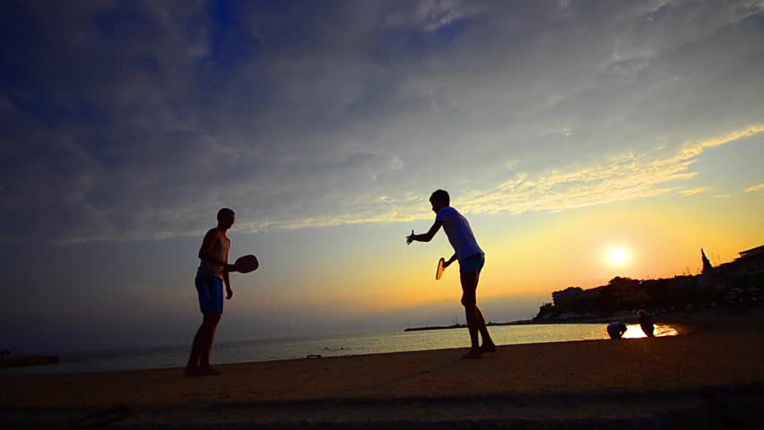 Beach leisure tennis game. Beautiful teen and handsome gay are having fun at the