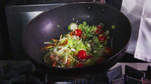 A stir fry meal being prepared in a hotel or restaurant kitchen flambe style. No faces can be seen.