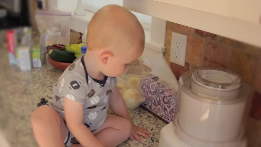 A baby boy exploring the kitchen while his mother cooks